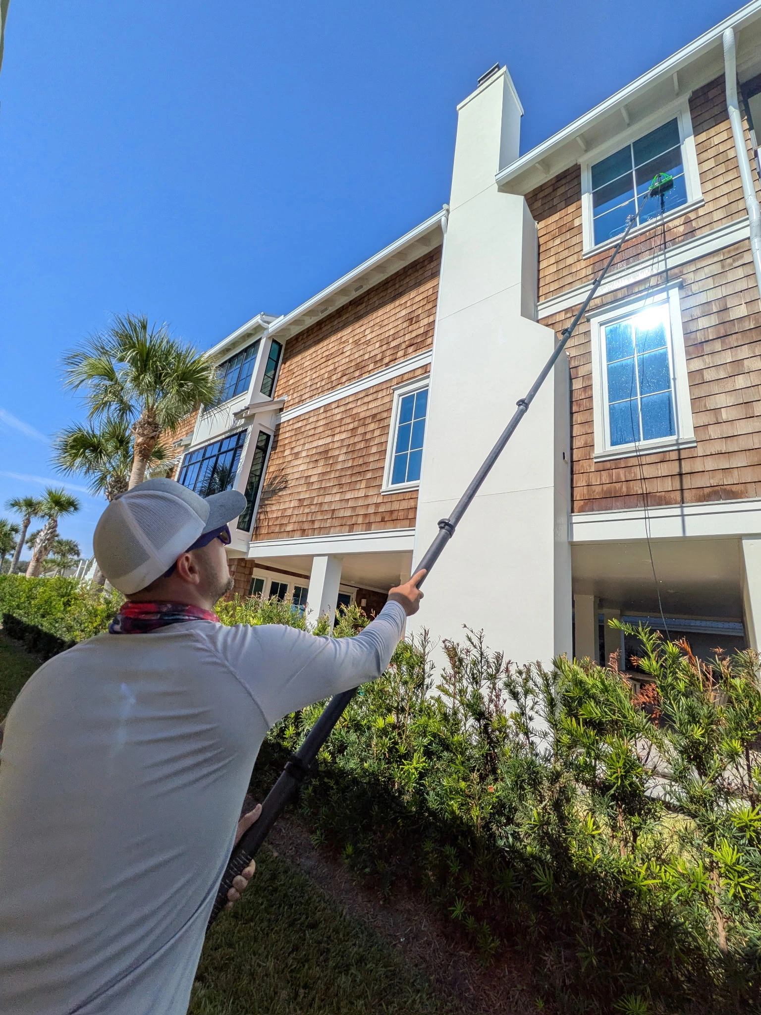 Technician cleaning upper windows at a Jacksonville Beach property